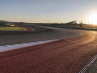 an image of a racetrack with a sunset in the background and a line of red