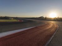 an image of a racetrack with a sunset in the background and a line of red