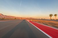 a photo of a dirt race track with sun setting in the distance of the track