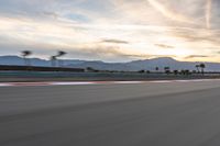 a photo of a dirt race track with sun setting in the distance of the track