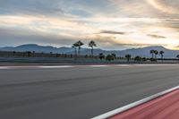 a photo of a dirt race track with sun setting in the distance of the track