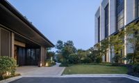 the courtyard of this modern building features trees and bushes as well as a paved walkway