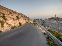 the curved road goes along the beach to a cliff shore at dusk on a clear, calm day