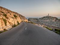 the curved road goes along the beach to a cliff shore at dusk on a clear, calm day