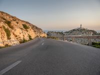 the curved road goes along the beach to a cliff shore at dusk on a clear, calm day