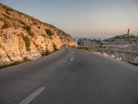 the curved road goes along the beach to a cliff shore at dusk on a clear, calm day