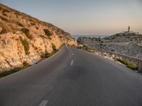 the curved road goes along the beach to a cliff shore at dusk on a clear, calm day