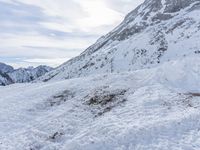 a skier walks down the trail of a snowy slope by a mountain ridge, in slow motion