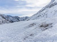 a skier walks down the trail of a snowy slope by a mountain ridge, in slow motion