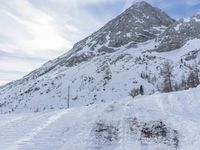 a skier walks down the trail of a snowy slope by a mountain ridge, in slow motion