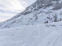 a skier walks down the trail of a snowy slope by a mountain ridge, in slow motion