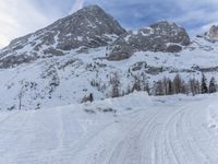 a skier walks down the trail of a snowy slope by a mountain ridge, in slow motion