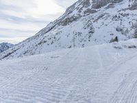 a skier walks down the trail of a snowy slope by a mountain ridge, in slow motion