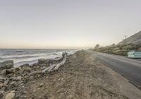 a car driving along the coast during a sunset time in california, usa with rocks and boulders