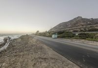 a car driving along the coast during a sunset time in california, usa with rocks and boulders