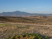 a motorcycle is parked in the desert beside a road while others sit by it on a hillside