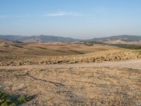 a motorcycle is parked in the desert beside a road while others sit by it on a hillside