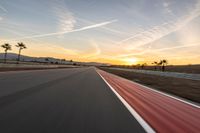 a photo of a dirt race track with sun setting in the distance of the track