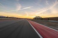 a photo of a dirt race track with sun setting in the distance of the track