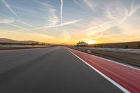 a photo of a dirt race track with sun setting in the distance of the track