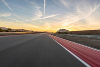 a photo of a dirt race track with sun setting in the distance of the track