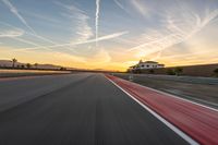 a photo of a dirt race track with sun setting in the distance of the track