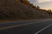 a motorcycle riding down a highway with trees in the background at dusk with no traffic