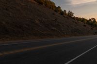 a motorcycle riding down a highway with trees in the background at dusk with no traffic