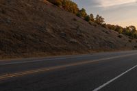 a motorcycle riding down a highway with trees in the background at dusk with no traffic