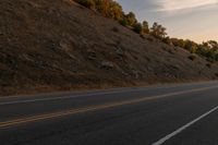 a motorcycle riding down a highway with trees in the background at dusk with no traffic