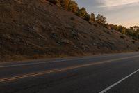 a motorcycle riding down a highway with trees in the background at dusk with no traffic