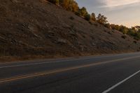 a motorcycle riding down a highway with trees in the background at dusk with no traffic