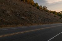 a motorcycle riding down a highway with trees in the background at dusk with no traffic