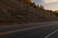 a motorcycle riding down a highway with trees in the background at dusk with no traffic