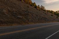 a motorcycle riding down a highway with trees in the background at dusk with no traffic