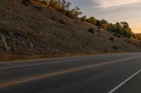 a motorcycle riding down a highway with trees in the background at dusk with no traffic