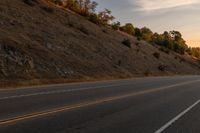 a motorcycle riding down a highway with trees in the background at dusk with no traffic