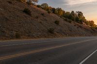 a motorcycle riding down a highway with trees in the background at dusk with no traffic