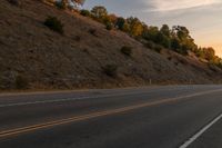 a motorcycle riding down a highway with trees in the background at dusk with no traffic