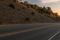 a motorcycle riding down a highway with trees in the background at dusk with no traffic