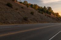 a motorcycle riding down a highway with trees in the background at dusk with no traffic