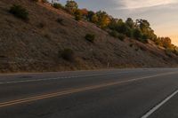 a motorcycle riding down a highway with trees in the background at dusk with no traffic