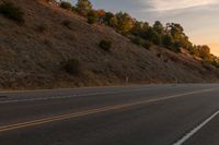 a motorcycle riding down a highway with trees in the background at dusk with no traffic