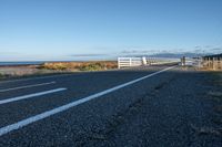 a rural road is pictured next to the ocean on a clear day with no clouds in sight