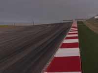 this is a runway in the countryside with a red and white stripe between it and some grass in the background