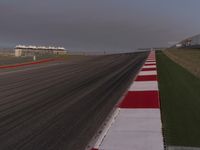 this is a runway in the countryside with a red and white stripe between it and some grass in the background