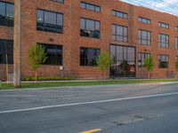 an empty street in front of a large red brick building on the other side of the road is a street light that has a line for motorists