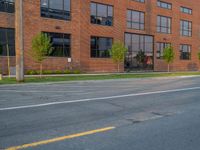 an empty street in front of a large red brick building on the other side of the road is a street light that has a line for motorists