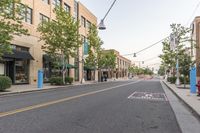 a street is filled with shopping stores and shops and people riding bikes and bicycles, and trees lining both sides of the street