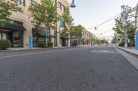 a street is filled with shopping stores and shops and people riding bikes and bicycles, and trees lining both sides of the street